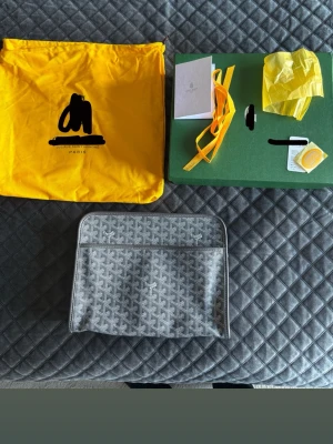 Grå datorväska med mönster - Snygg grå datorväska med det klassiska vita mönstret. Väskan har dragkedja upptill, två ytterfack och detaljer i läder. Perfekt för att bära laptop och viktiga prylar. Kommer med originalpåse och tillbehör.
