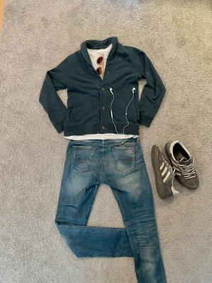 Marinblå Cardigan - Mysig mörkblå Cardigan med sjalkrage och fyra knappar framtill. Två fickor på framsidan och ribbade muddar vid ärmslut och nederkant. Perfekt för lager på lager och enkel att matcha. Storlek = 158cm men passar även 160cm+ eftersom jag är 172cm och den passar nästan mig. Hör av er vid frågor!