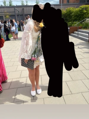 Vit omlottklänning med volanger - Söt vit kortklänning med omlott och volangdetaljer. Klänningen har långärmade, transparenta ärmar och ett diskret blommigt mönster i tyget. Perfekt för sommarens alla tillfällen och har en romantisk känsla med sina fina detaljer.💕