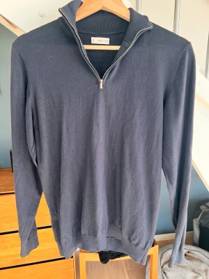 Mörkblå halvzip tröja från MNG - Stilren mörkblå tröja från MNG med halvzip och hög krage. Tillverkad i ett tunt, mjukt material som passar perfekt till lager på lager. Långa ärmar och ribbade muddar vid ärmslut och nederkant ger en klassisk look.