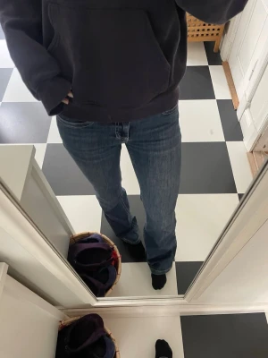 Nelly jeans - Mörkblå bootcut jeans med vita broderade detaljer på bakfickorna. Klassisk femficksmodell med hög midja och dubbla knappar framtill. Tillverkade i stretchig denim för skön passform. Lite slitna vid hälen men annars bra skick