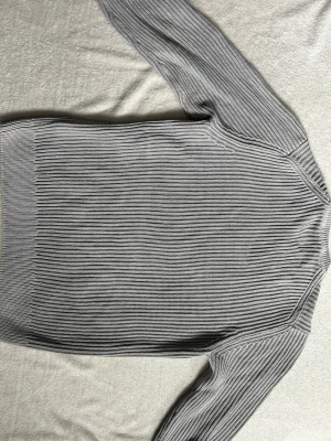 Grå ribbstickad tröja från Vailent - Snygg grå ribbstickad tröja från Vaillent med rund halsringning och långa ärmar. Tröjan har en clean look med breda muddar vid ärmslut och nederkant. Perfekt för lager på lager och enkel att matcha med olika outfits. Orginalpris - 600kr 