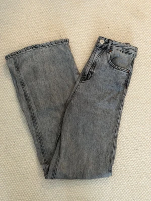 Gråa jeans - Säljer ett par gråa jeans från stradivarius i storlek 32. Modellen är högmidjad och har vida ben.