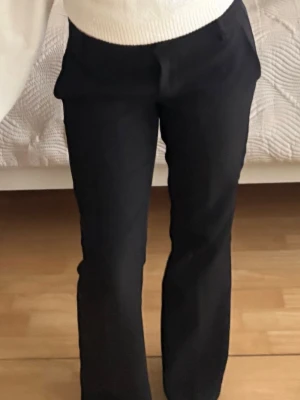 Svarta raka kostymbyxor  - Säljer ett par svarta kostymbyxor med rak passform och pressveck. Byxorna har diskreta sidofickor och sitter snyggt i midjan. Perfekta till en stilren look och passar till många olika outfits. Storlek 34 petite
