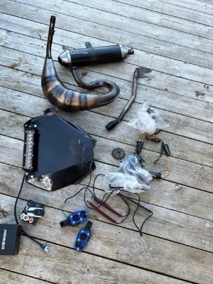 Mopeddelar och avgassystem - Säljer ett paket med mopeddelar inklusive ett avgassystem från Leovince, kåpa med LED-ljus, blinkers, bromsok i blått, kedjehjul, backspeglar och diverse kablar. Perfekt för dig som vill meka eller uppgradera din moped.