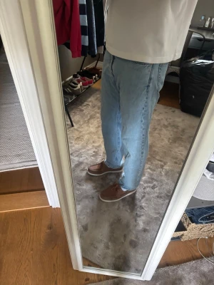 Ljusblå raka jeans - Säljer ett par ljusblå jeans med rak passform och klassisk femficksdesign. Jeansen har normal midja och stängs med dragkedja och knapp. Perfekta till en avslappnad stil.