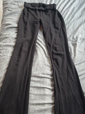 Svarta utsvängda leggings - Säljer ett par svarta leggings med utsvängda ben och hög midja. Materialet är stretchigt och mjukt, perfekt för en trendig och bekväm look. Passar till många olika stilar och är riktigt sköna att ha på sig.