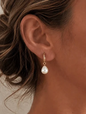 Guldörhänge med droppformad pärla - Stilrent örhänge i guld med en droppformad vit pärla som hänger elegant. Perfekt för dig som gillar klassiska smycken med en modern twist. Lätt att matcha med olika looks och ger en lyxig känsla.