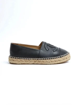 Svarta loafers i läder med flätad sula - Snygga svarta loafers från Chanel i mjukt läder med det klassiska CC-logotypen på ovansidan. Skorna har en rundad tå och en grov, flätad sula i naturfärgad jute som ger en cool kontrast till det svarta lädret. Perfekta för en trendig och avslappnad stil.