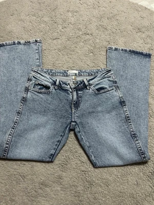Ljusblå raka jeans med broderad ficka - Säljer ett par ljusblå jeans med raka ben och snygg broderad detalj på bakfickan. Jeansen har klassisk femficksdesign och är gjorda i ett slitstarkt denimtyg. Perfekta för dig som gillar en avslappnad och tidlös look.