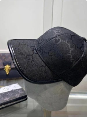 Svart keps med GG-mönster - Snygg svart keps med diskret GG-monogram över hela ytan. Kepsen har böjd skärm och detaljer i svart läder längs kanten. Perfekt accessoar för en trendig och stilren look.