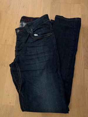 Mörkblå raka jeans - Snygga mörkblå jeans med raka ben och klassiska kontrastsömmar. Jeansen har fem fickor och knappgylf. Passar perfekt till en avslappnad stil och är tillverkade i ett mjukt denimtyg.       Obs! Upplagda från längd 32 till längd 30! 