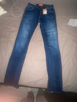 Blå skinny jeans från Jack & Jones - Snygga blå skinny jeans från Jack & Jones med klassisk femficksdesign och tydliga kontrastsömmar. Jeansen har en smal passform och är tillverkade i stretchigt denim för extra komfort. Perfekta för dig som gillar en modern och slimmad look.