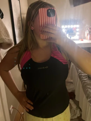 Svart och rosa träningstopp SOC - Säljer ett svart träningslinne från SOC med rosa axelpartier och racerback. Linnet har en sportig passform och är tillverkat i ett stretchigt funktionsmaterial som andas, perfekt för gymmet eller löprundan.