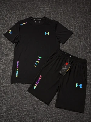 Svart träningsset från Under Armour - Säljer ett svart träningsset från Under Armour med t-shirt och shorts. Setet har färgglada loggor och detaljer i regnbågsfärger. Tillverkat i ett lätt och snabbtorkande material som passar perfekt för träning och sportaktiviteter.