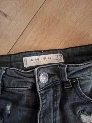 Grå jeansshorts med spets från new yorker men märket heter amisu  - Säljer ett par grå jeansshorts från new yorker med snygga slitningar och vita spetsdetaljer längst ner. Shortsen har klassisk femficksdesign, bälteshällor och knappstängning framtill. Perfekta för dig som vill ha en cool och feminin stil i sommar!