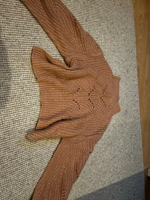 Brun stickad tröja med mönster - Säljer en snygg brun stickad tröja med hålmönster och hög hals. Tröjan har långa ärmar och är gjord i ett tjockare garn som ger en mysig känsla. Perfekt för kyligare dagar och enkel att styla till jeans eller kjol. Finns ej lappar inuti! Pris diskuteras 🩷