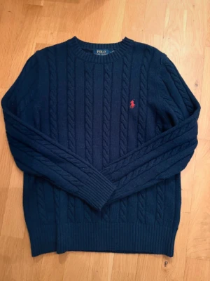 Ralph lauren sweater  - En marinblåa Ralph Lauren kabelstickad Sweater/tröja. Storlek L men sitter mer som M. Tröjan är i väldigt bra skick, säljs då den endast sitter i garderoben.