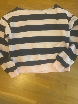 Randig sweatshirt från Lager 157  - Mysig sweatshirt från Lager 157 i storlek XS. Tröjan har breda marinblå och ljusrosa ränder, rund halsringning och ribbade muddar. Perfekt för en avslappnad och trendig look. Tillverkad i mjukt bomullsmaterial.