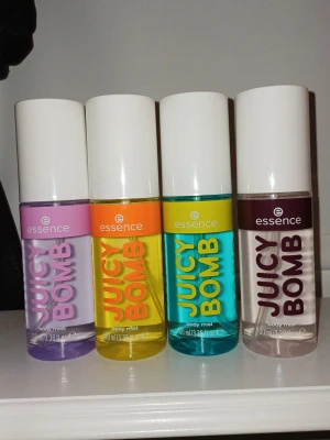 Essence Juicy Bomb Body Mist 4-pack - Fyra färgglada Essence Juicy Bomb body mist i olika dofter. Flaskorna är i plast med vita lock och har färgerna lila, gul, turkos och brun. Varje flaska rymmer 100 ml och har en modern, ungdomlig design med tydlig logga och text. I dofterna Blueberry Bite, Caramel Cloud, Coconut Chill & Cookie Crazy.