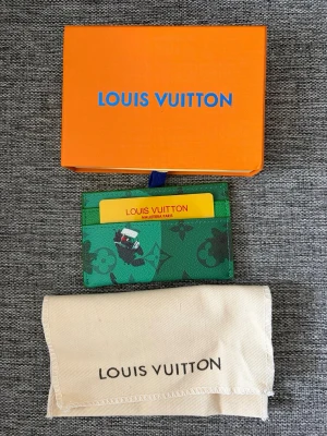 LV korthållare - Säljer ett snyggt grönt kortfodral från Louis Vuitton med monogrammönster och golfmotiv. Fodralet har flera kortfack och är gjort i tåligt läder. Kommer med original ask och dustbag. Perfekt för dig som vill ha något unikt och stilrent i fickan.