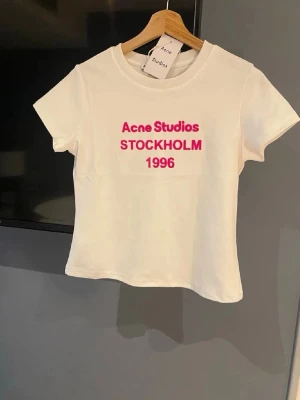 Vit Acne Studios t-shirt med tryck - Säljer min snygga Acne Studios t-shirt som är äkta och helt oanvänd. Det enda som saknas är prislappen från bilden men säljer för sjukt bra pris och denna tröja är även svår att få tag på. Originalpris 3000