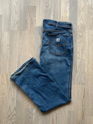 Carhartt Jeans Original Fit - Regular 16 - Mycket bra skick. Liten fläck, annars inga tecken på användning  Jeans från Carhartt, storlek 16, blå Minimalistiska, blå jeans (original fit) i regular fit. Elastiskt material och formbar passform. Bakficka med Carhartt-loggan, knapp och dragkedjegylf, lätt fransning.  Midjemått - 90 cm Beninnerlängd - 80 cm ≈ W35 L32 (UPPSKATTAD MOTSVARANDE STORLEK) 77% bomull, 21% polyester, 2% spandex Liten fläck, se bild