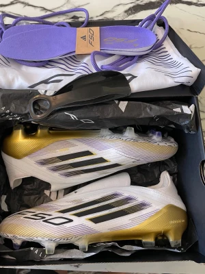 Adidas F50 fotbollsskor FG Elite vit/guld - Säljer ett par Adidas F50 FG Elite fotbollsskor i vitt och guld med svarta detaljer och klassiska tre ränder. 