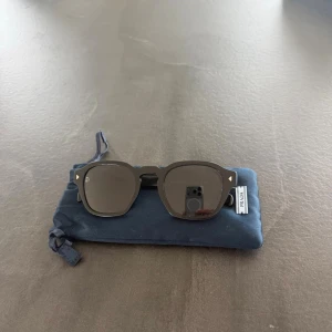  Prada solglasögon - Svarta solglasögon från Prada i unisexmodell med raka bågar. Har mörka glas och mjuk påse med dragsko. Hårt fodral mjukt fodral samt duk tillföljer Köpta från Farfetch för 4900 kr