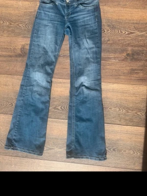 Blå bootcut jeans med utsvängda ben - Snygga blå bootcut jeans med utsvängda ben från Nelly. Super sköna! Inga skavanker förutom att sömmen från ena baksida ficka har lossnat lite (se sista bild), annars super fina!❣️