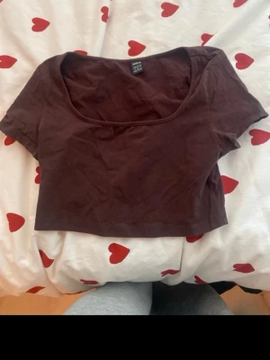 Mörkbrun croppad topp från SHEIN - Snygg mörkbrun croppad topp från SHEIN med korta ärmar och rundad urringning. Perfekt till jeans eller kjol för en trendig look. Tillverkad i mjukt material som känns skönt mot huden.