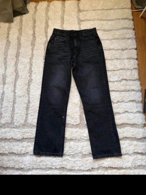 Svarta raka jeans - Säljer ett par svarta jeans med rak passform och klassisk femficksdesign. Jeansen har en lätt tvättad look och normal midja. Perfekta för en avslappnad och stilren outfit.