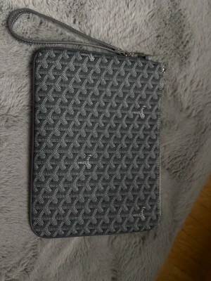 Grå mönstrad datorväska - Snygg grå kuvertväska med klassiskt grafiskt mönster och handledsrem. Väskan har dragkedja upptill och är tillverkad i ett tåligt material med en lyxig känsla. Perfekt för att bära det viktigaste eller använda som datorväska. Pris kan diskuteras!🌸🌸 