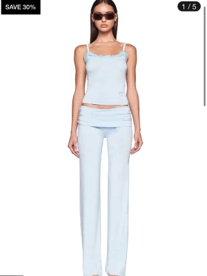 Ljusblått och rosa loungewear-set - Säljer ett mjukt och stretchigt loungewear-set i ljusblått. Setet består av ett linne med smala axelband och spetskant samt matchande byxor med låg midja och utsvängda ben. Perfekt för chill dagar hemma. OBS settet är oanvänt dvs i nyskick och kan inte längre köpas!