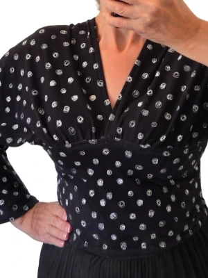Svart blus med vita prickar och v-ringning stl S - Snygg svart blus med vita prickar och djup v-ringning. Blusen har lång ärm och markerad midja som ger en feminin siluett. Materialet ser ut att vara mjukt och följsamt, perfekt för en trendig look.
