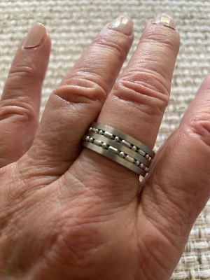 Stilren silverfärgad ring i rostfritt stål - Säljer en cool och stilren ring i silverfärgat rostfritt stål. Ringen har två rader med små kuldetaljer runt om som ger en modern och edgy känsla. Perfekt för dig som gillar minimalistiska accessoarer med en twist. Unisex. Storlek 19 mm. Italiensk design som levereras i smyckesask