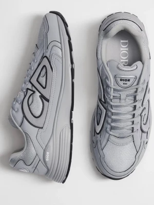 Grå Dior sneakers med CD-detalj - Snygga grå sneakers från Dior med stora CD-detaljer på sidan. Skorna har en chunky sula, meshpaneler och läderdetaljer för en modern look. Perfekta för dig som vill ha en stilren och exklusiv sneaker med tydlig logga.