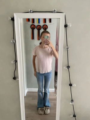 Ljusrosa basic t-shirt - En enkel och stilren ljusrosa t-shirt med rund hals och korta ärmar. T-shirten har en avslappnad passform och är tillverkad i ett mjukt material som känns skönt mot huden. Perfekt att matcha med jeans eller kjol för en clean look.