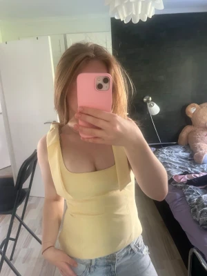 Zara topp - Snygg ljusgul linnetopp med breda axelband och fyrkantig urringning. Toppen har en figurnära passform och är perfekt för varma dagar. Materialet känns mjukt och lätt mot huden. Matcha med jeans eller kjol för en fräsch look.