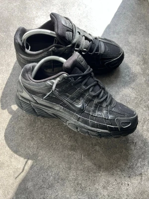 Nike p-6000 - Snygga helsvarta Nike sneakers med cool design i mesh och läderdetaljer. Skorna har lågt skaft, klassiska snörningar och diskret Nike-logga på sidan. Perfekta för dig som gillar en stilren och sportig look. Använt dem typ 4 gånger o dem är lite slitna på sidorna av skorna.