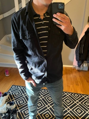 Mörkblå overshirt - Stilren mörkblå overshirt med två bröstfickor och knäppning framtill. Overshirten har klassisk krage och långa ärmar, perfekt att slänga på sig över en t-shirt. Materialet är mjukt och bekvämt, passar till många olika outfits.