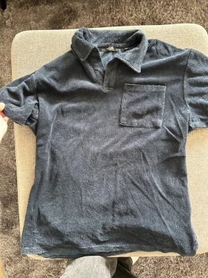 Mörkblå frottéskjorta Jack & Jones - Snygg mörkblå skjorta från Jack & Jones i mjuk frotté. Skjortan har korta ärmar, klassisk krage och en bröstficka. Perfekt för en avslappnad och trendig stil. Materialet är frotté som ger en unik känsla och look.