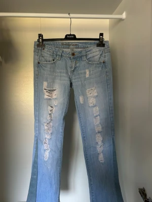 Ljusblåa jeans med hål i - Säljer ett par jättefina och unika jeans för att de tyvärr blivit för små, sytt bootcuten själv. Använt en gång!😊😊