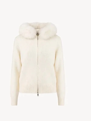 Vit stickad alessa cardigan med fuskpäls - Mysig vit stickad alessa cardigan med dragkedja och huva dekorerad med fluffig fuskpäls. Långärmad modell med ribbade muddar och nederkant. Perfekt för kyliga dagar när du vill vara både varm och snygg.