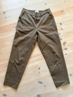 Gröna chinos från Object, strl 38 - Snygga gröna chinos från Object i storlek 38. Byxorna har en avslappnad passform, resår i midjan och sidofickor. Tillverkade i ett mjukt och bekvämt material som passar perfekt till en trendig vardagslook.