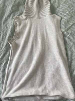 Beige ribbad polotopp från Zara köp era bogs - Säljer en beige ribbad polotopp från Zara. Toppen är ärmlös med hög polokrage och har en mjuk, stretchig känsla. Perfekt att styla med jeans eller kjol för en clean och trendig look.