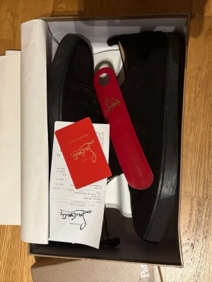Svarta mockasneakers från Louboutin - Säljer ett par svarta sneakers från Louboutin i mjuk mocka med klassisk röd sula. Skorna har snörning och en stilren, låg profil som passar perfekt till streetwear eller en clean look. Kommer med originalkartong och skohorn.