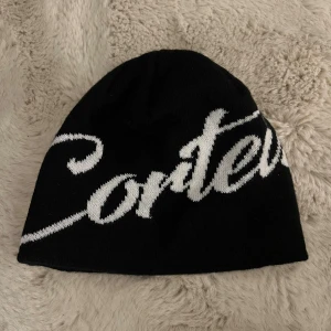 Svart mössa Corteiz  - Svart mössa från Corteiz med stor vit logotyp 