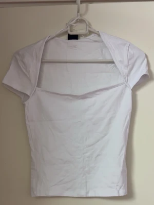 Vit croppad topp med kort ärm - Snygg vit croppad topp med korta ärmar och ”fyrkantig” urringning. Enkel och stilren design som passar till många outfits. Passar xs/s. Ny utan prislapp, aldrig använt. Se bion🫶🏻