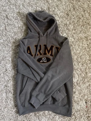 Vintage hoodie - Säljer en grå hoodie från ouray sportswear. På bröstet står det 'ARMY' i stora bokstäver med svart och gult tryck samt ett A-märke under. Perfekt för en avslappnad och cool stil. Hör av er vid minsta fundering! 😁